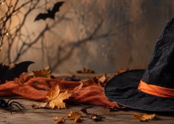 Sombrero de bruja negro sobre una mesa de madera con hojas de otoño y decoración de Halloween