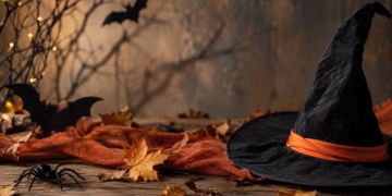 Sombrero de bruja negro sobre una mesa de madera con hojas de otoño y decoración de Halloween