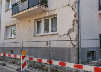 Fachada de un edificio de viviendas con grietas y vallas de obra, imagen genérica