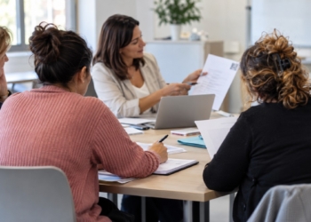 Grupo de mujeres participa en un taller de orientación laboral con una formadora y documentos sobre una mesa